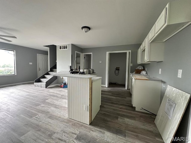 kitchen featuring dark wood-style flooring, white cabinetry, baseboards, ceiling fan, and light countertops