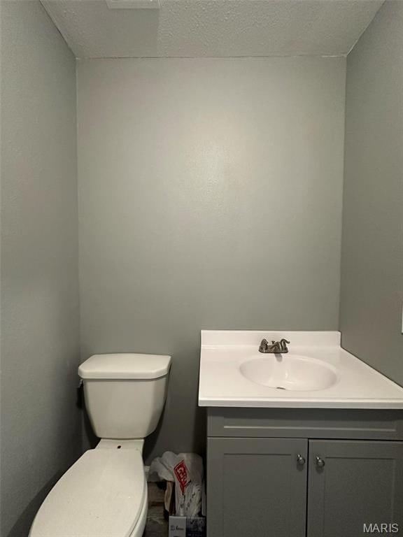 half bath featuring vanity and toilet