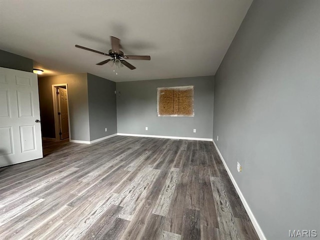 spare room featuring a ceiling fan, dark wood-type flooring, and baseboards