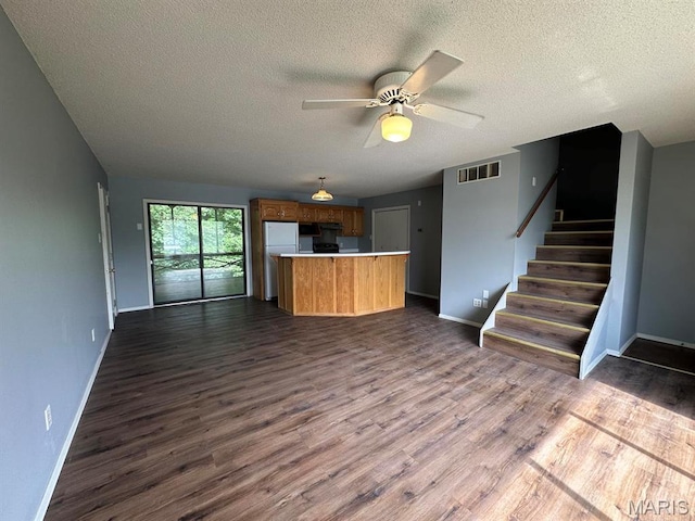 kitchen with open floor plan, a textured ceiling, dark wood-type flooring, baseboards, and light countertops