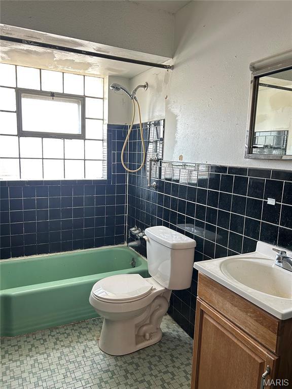 3757 Itaska St, Saint Louis, MO 63116 - bathroom featuring toilet, tile walls, shower / bathtub combination, vanity, and a wainscoted wall