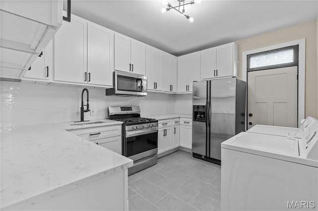 2220 Nebraska Ave, Saint Louis, MO 63104 - kitchen featuring stainless steel appliances, separate washer and dryer, a sink, white cabinetry, and decorative backsplash