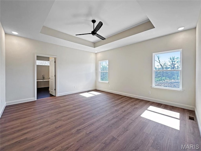 204 Great Bear Pass, Foristell, MO 63348 - unfurnished bedroom featuring a tray ceiling, dark wood-style floors, baseboards, ensuite bath, and recessed lighting