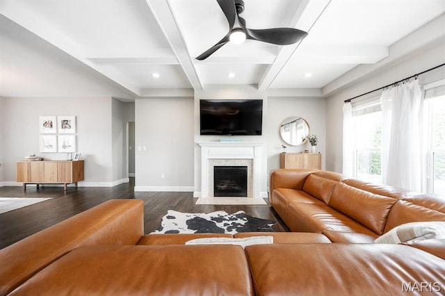 living room featuring beam ceiling, dark wood-type flooring, baseboards, a premium fireplace, and ceiling fan