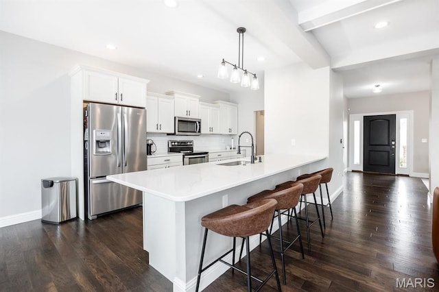 kitchen with stainless steel appliances, a sink, a kitchen breakfast bar, dark wood-style floors, and white cabinets