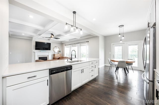 kitchen with appliances with stainless steel finishes, a sink, a ceiling fan, beam ceiling, and a fireplace
