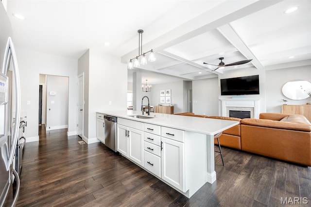 kitchen featuring stainless steel appliances, a sink, a ceiling fan, a fireplace, and dark wood finished floors