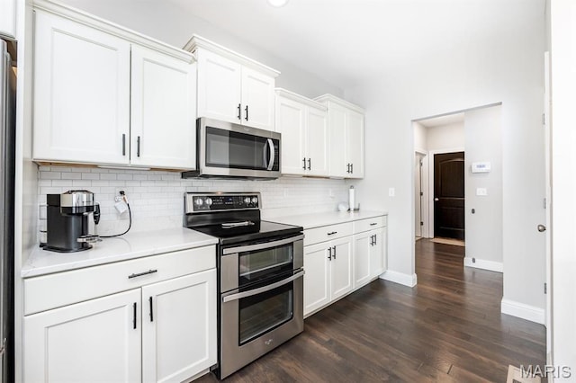kitchen featuring stainless steel appliances, backsplash, dark wood finished floors, baseboards, and light countertops
