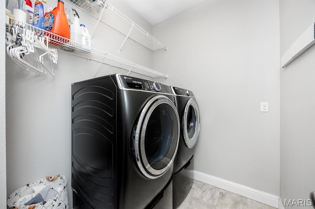 washroom with washing machine and clothes dryer, baseboards, and light marble finish flooring