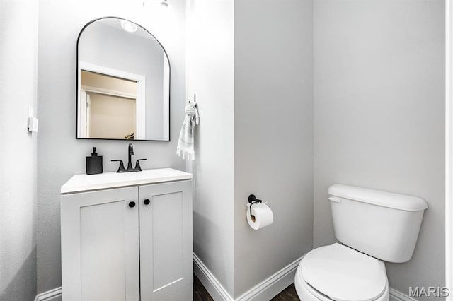 bathroom featuring toilet, vanity, and baseboards