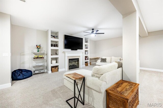 carpeted living room with a ceiling fan, a glass covered fireplace, built in features, and baseboards