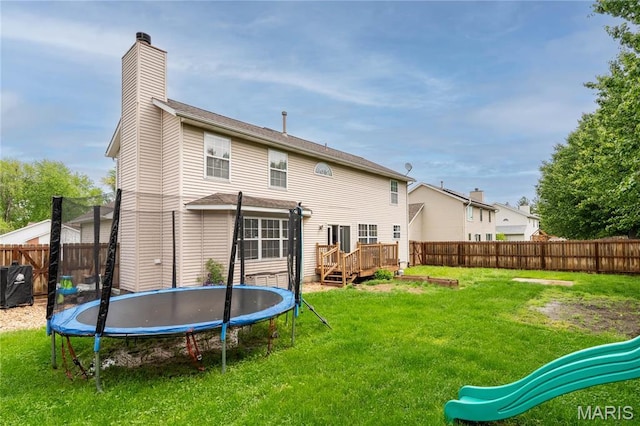 back of property featuring a trampoline, a chimney, a deck, and a playground