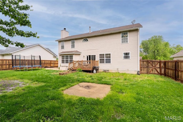 rear view of house with a trampoline, a deck, and a chimney