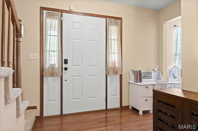 foyer entrance featuring wood finished floors, stairway, and baseboards