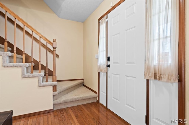 foyer entrance with wood finished floors, stairs, and baseboards