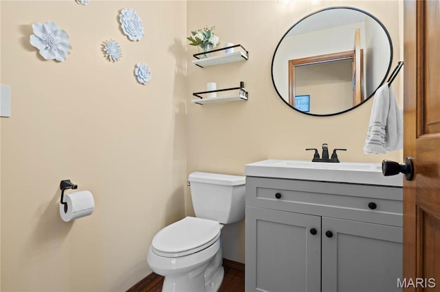 bathroom featuring vanity, toilet, wood finished floors, and baseboards