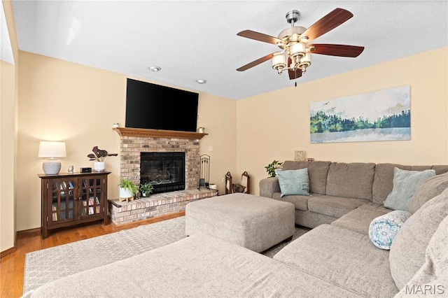 living area with a ceiling fan, wood finished floors, a fireplace, and recessed lighting
