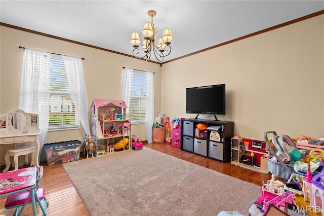 game room featuring ornamental molding, a chandelier, wood finished floors, and a textured ceiling