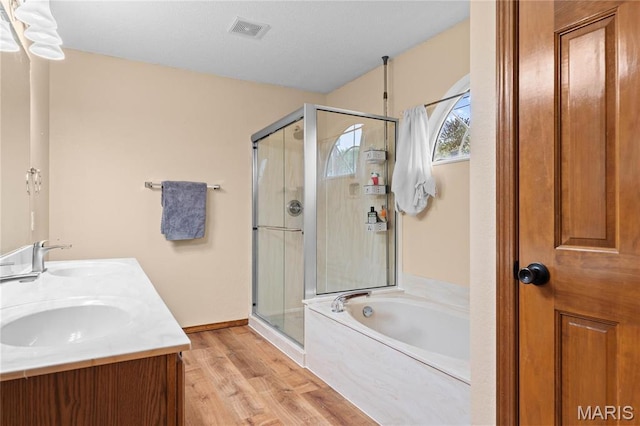 full bathroom with a shower stall, a garden tub, wood finished floors, and double vanity