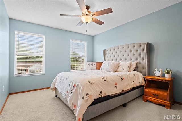 carpeted bedroom featuring baseboards, ceiling fan, and a textured ceiling