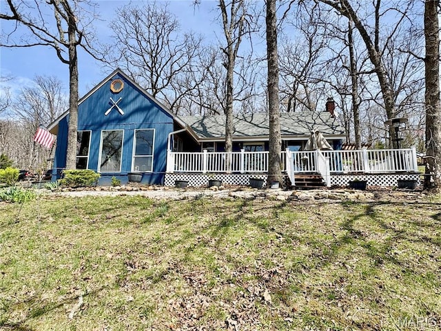 view of front of home featuring a front lawn, a chimney, and a deck