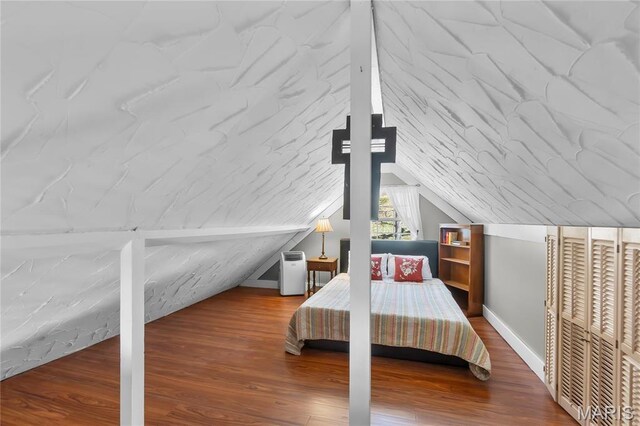 bedroom with wood finished floors, baseboards, and lofted ceiling