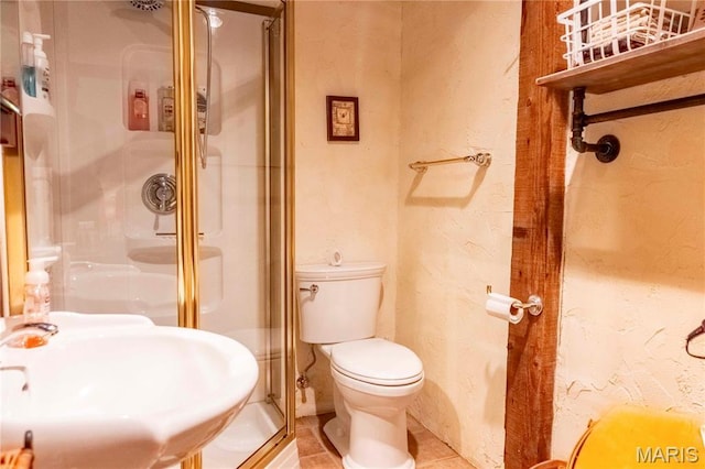 full bathroom with a sink, a shower stall, toilet, tile patterned flooring, and a textured wall
