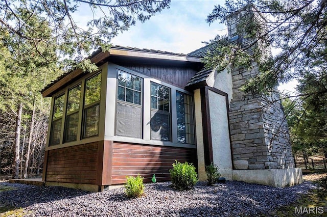 view of side of home with a sunroom and a chimney