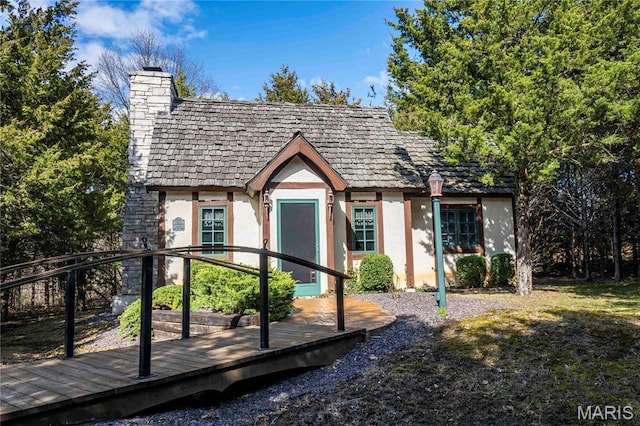 view of front of home with stucco siding, a chimney, and a deck