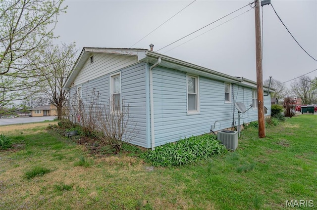 view of side of property with central AC and a lawn