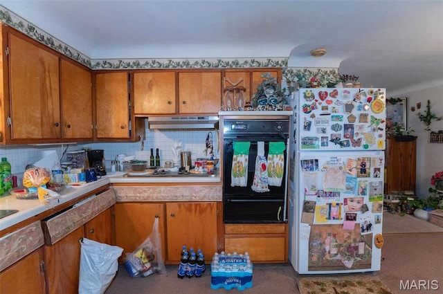 kitchen featuring freestanding refrigerator, oven, a warming drawer, brown cabinetry, and under cabinet range hood
