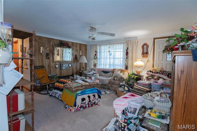 carpeted living room featuring ceiling fan and wood walls