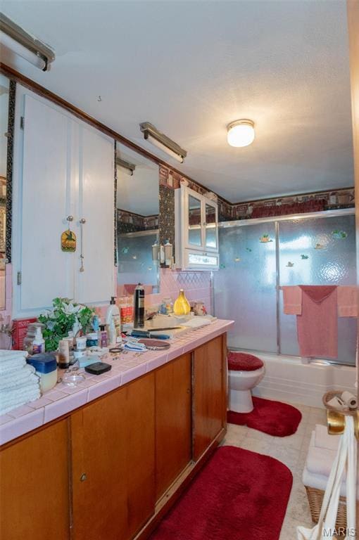 bathroom featuring toilet, vanity, and combined bath / shower with glass door