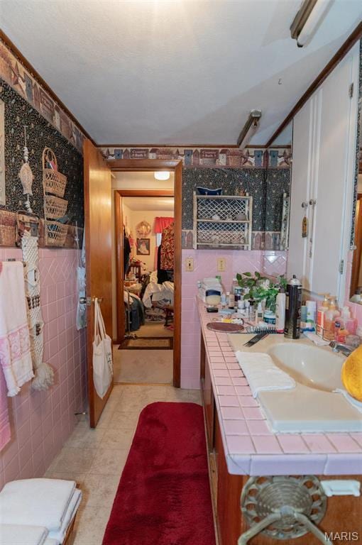 bathroom with tile walls, a shower, vanity, and tile patterned flooring
