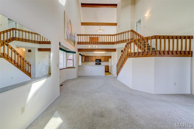 228 Hemingway Ln Unit F, Weldon Spring, MO 63304 - unfurnished living room featuring a towering ceiling, stairway, light carpet, ceiling fan, and baseboards