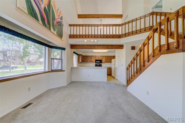 228 Hemingway Ln Unit F, Weldon Spring, MO 63304 - unfurnished living room featuring a high ceiling, light carpet, and stairs