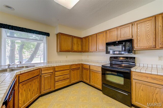 228 Hemingway Ln Unit F, Weldon Spring, MO 63304 - kitchen featuring black appliances, tile countertops, a sink, brown cabinets, and a textured ceiling