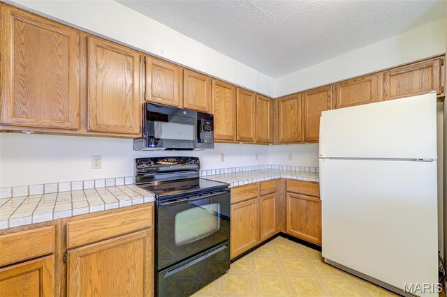 228 Hemingway Ln Unit F, Weldon Spring, MO 63304 - kitchen featuring black appliances, tile counters, a textured ceiling, and brown cabinets
