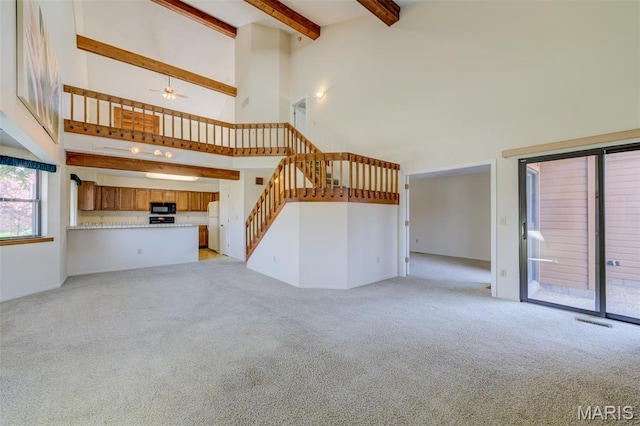 228 Hemingway Ln Unit F, Weldon Spring, MO 63304 - unfurnished living room featuring a high ceiling, light carpet, beam ceiling, stairway, and a ceiling fan
