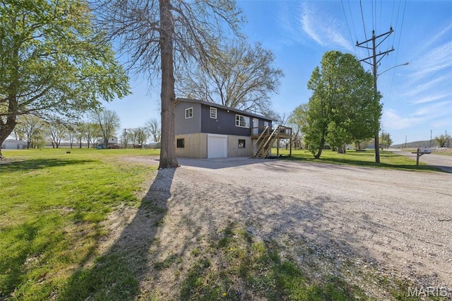 view of front of property featuring stairway, an attached garage, dirt driveway, and a front lawn