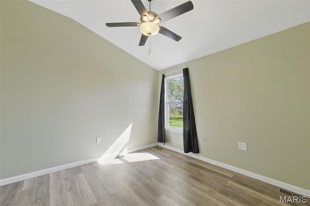 unfurnished room featuring vaulted ceiling, a ceiling fan, wood finished floors, and baseboards