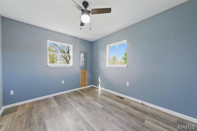empty room featuring healthy amount of natural light, ceiling fan, and wood finished floors
