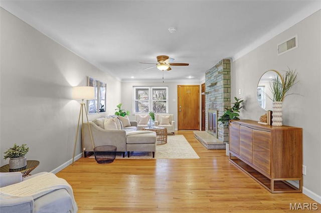 living room featuring light wood-style floors, a ceiling fan, and baseboards
