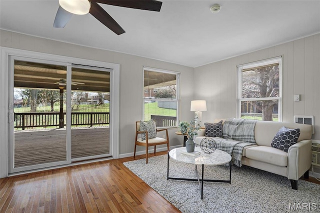 living room featuring ceiling fan, hardwood / wood-style floors, healthy amount of natural light, and baseboards