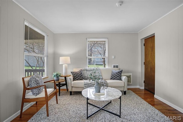 living area with wood finished floors, baseboards, and ornamental molding