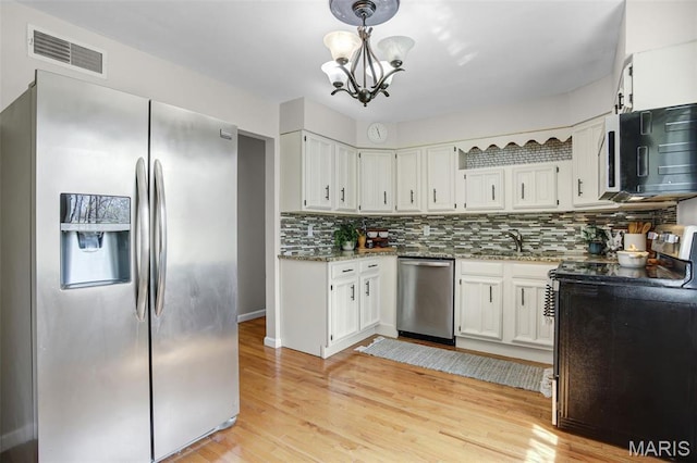 kitchen featuring appliances with stainless steel finishes, decorative backsplash, stone countertops, a chandelier, and white cabinetry