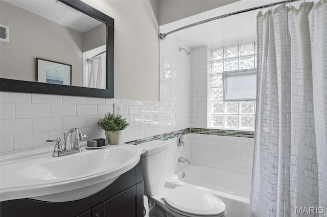 full bathroom with toilet, vanity, shower / tub combo, backsplash, and tile walls