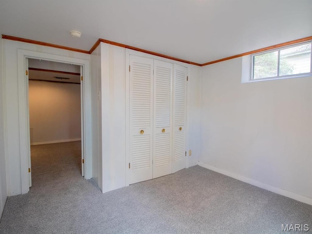 unfurnished bedroom featuring carpet floors, ornamental molding, a closet, and baseboards