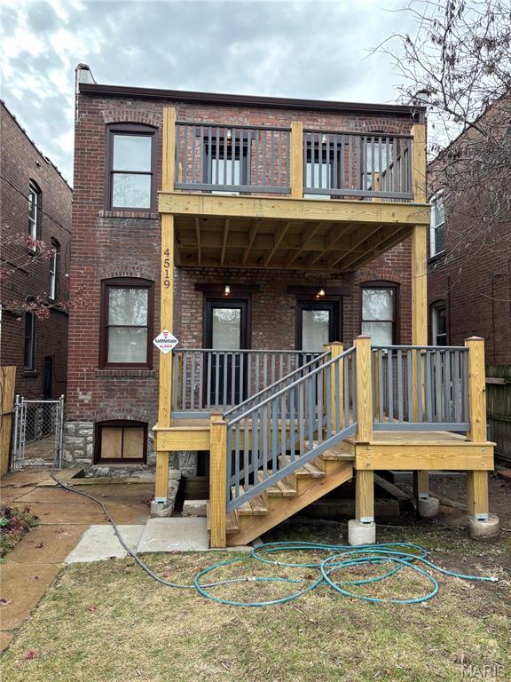 4519 Flora Ave, Saint Louis, MO 63110 - view of front of house featuring a balcony, brick siding, fence, and a gate