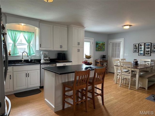 404 Crystal Ln, Rosebud, MO 63091 - kitchen with appliances with stainless steel finishes, a sink, dark countertops, light wood-style flooring, and a kitchen breakfast bar